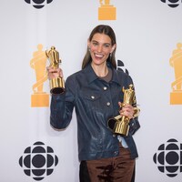 Charlotte Cardin pose pour la caméra en tenant des trophées Juno.