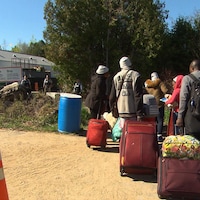 Des migrants se rendent au Canada par le chemin Roxham alors que des agents de la GRC les attendent de l'autre côté de la frontière. 