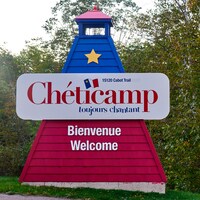 Un phare aux couleurs de l'Acadie avec l'écriteau Chéticamp.