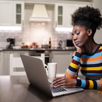 Une femme noire à la recherche d'un emploi devant son ordinateur.