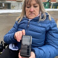 Une femme sur un fauteuil roulant tenant un téléphone cellulaire.
