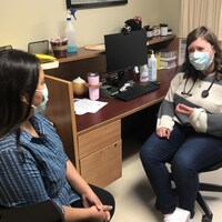 Une femme autochtone consulte une infirmière, toutes deux masquées.