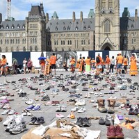 De nombreuses paires de chaussures couvrent le sol devant la colline du Parlement à Ottawa.
