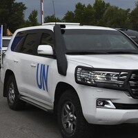 Des véhicules de l'ONU circulent sur une route.