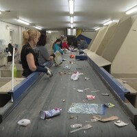 Des employés sont à l'œuvre au centre de tri de matières recyclables.