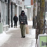 Un homme qui porte un couvre-visage déambule sur la rue Saint-Germain à Rimouski.