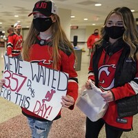 Deux jeunes femmes masquées dans un hall, portant l'uniforme des Devils. L'une d'elles tient une affiche où il est écrit, en anglais : "Nous avons attendu 357 jours pour cette journée."