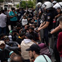 Des migrants manifestent encerclés par des policiers. 