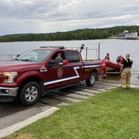 Une camionnette de pompiers sort un bateau pneumatique de l'eau.