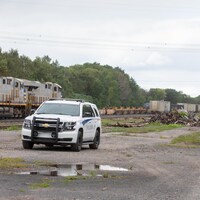 Une voiture de police devant une locomotive immobilisée.
