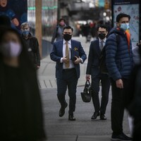 Des personnes dans la rue portant un masque.