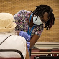 Une femme administre une dose de vaccin à une personne âgée. 