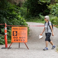 Une femme marche devant une pancarte annonçant la fermeture du parc.