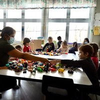 Des enfants s'amusent avec des jouets en compagnie de leur éducatrice, dans un centre de la petite enfance.                          