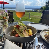 Des mets et un verre de rosé sur une table extérieure avec vue sur la mer des Salish.