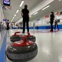 Des joueuses de curling et une pierre de curling à l'avant plan.