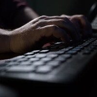 Les doigts d'un homme tapent sur un clavier d'ordinateur.