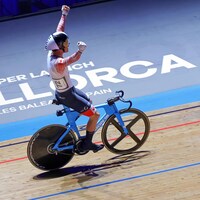 Mathias Guillemette, en piste sur son vélo, lève les bras dans les airs en signe de victoire. 