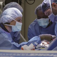 Quatre médecins dans un bloc opératoire se concentrent sur leur tâche.