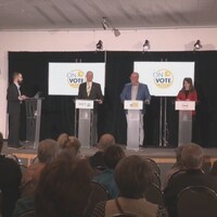 Trois hommes et une femme chacun devant un podium.