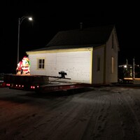 La maison est déplacée sur la remorque d'un camion en pleine nuit. 