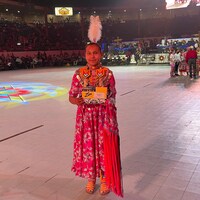 Demi Potts de la Nation sioux des Nakotas d'Alexis est debout en costume traditionnel au milieu d'un stade après avoir remporté la première place au pow-wow de l'assemblée des nations.