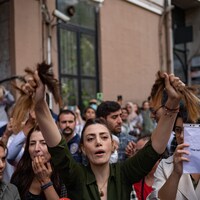 Une Iranienne vivant en Turquie brandit ses cheveux après les avoir coupés avec une paire de ciseaux. 