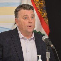 Dennis King lors d'une conférence de presse devant le drapeau de l'Île-du-Prince-Édouard.