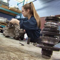 Une jeune femme travaille sur un moteur.