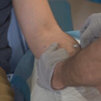Un professionnel de la santé pique une seringue dans le bras d'un patient.