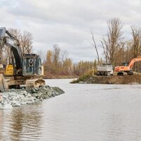 Des bulldozers qui oeuvrent à réparer la digue Sumas, à Abbotsford, après des inondations.