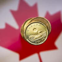 Une pile de dollars canadiens sur un drapeau du Canada.