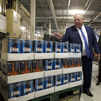 Un homme à côté d'une pile de caisses de bière