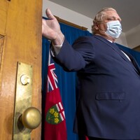 Doug Ford porte le masque et s'apprête à fermer une porte.