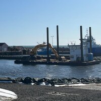 Une excavatrice sur une barge dans le quai de l'île d'Entrée.