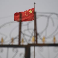 Des barbelés devant un drapeau de la Chine. 