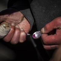 Un personne prépare une injection de drogue.