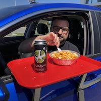 Un client installé dans sa voiture mange une poutine.