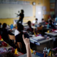 Un enfant lève le doigt dans une salle de classe.