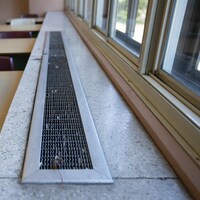 Une bouche de ventilation, devant des fenêtres.
