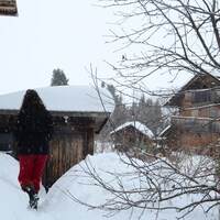 Dans un paysage hivernal, une femme marche à travers des maisons de style alpin