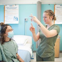 Une étudiante en soins infirmiers prépare une seringue pour une patiente.