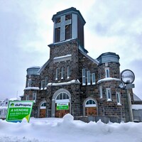 Des affiches "à vendre" sont plantées dans la neige devant l'église et installée sur la porte principale de l'édifice.
