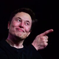 Elon Musk montre quelque chose du doigt.