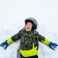 Un enfant fait un ange dans la neige.