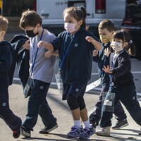 Des enfants qui portent le masque traversent la rue.