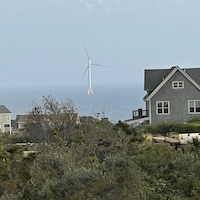 Une éolienne en mer devant une maison à Block Island.