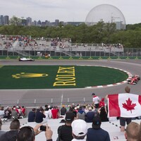 Séance d'essais libres du Grand Prix du Canada, au circuit Gilles-Villeneuve de l'île Notre-Dame, où l'on aperçoit des spectateurs dans les gradins, deux voitures en action, la Biosphère et le centre-ville de Montréal en arrière-plan.