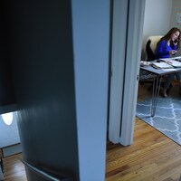 Une étudiante dans une chambre devant un ordinateur parle au téléphone.
