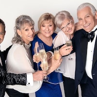 Deux hommes et trois femmes sont tout sourire, verre de champagne en main, sur fond blanc. 